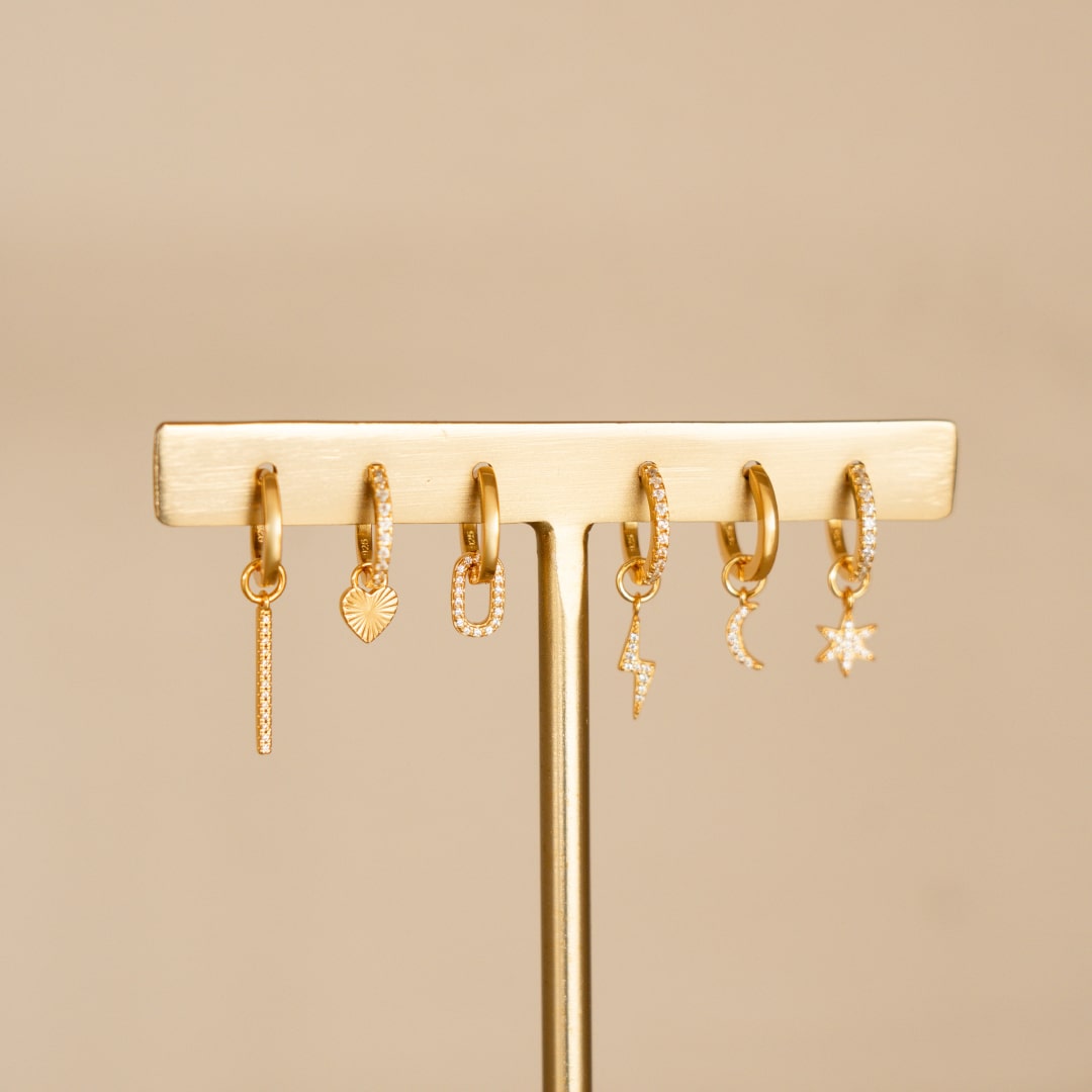 Verzameling van gouden huggie hoop oorbellen van Bedels & Bedels, gecombineerd met verschillende bedels voor een stijlvolle en persoonlijke uitstraling.