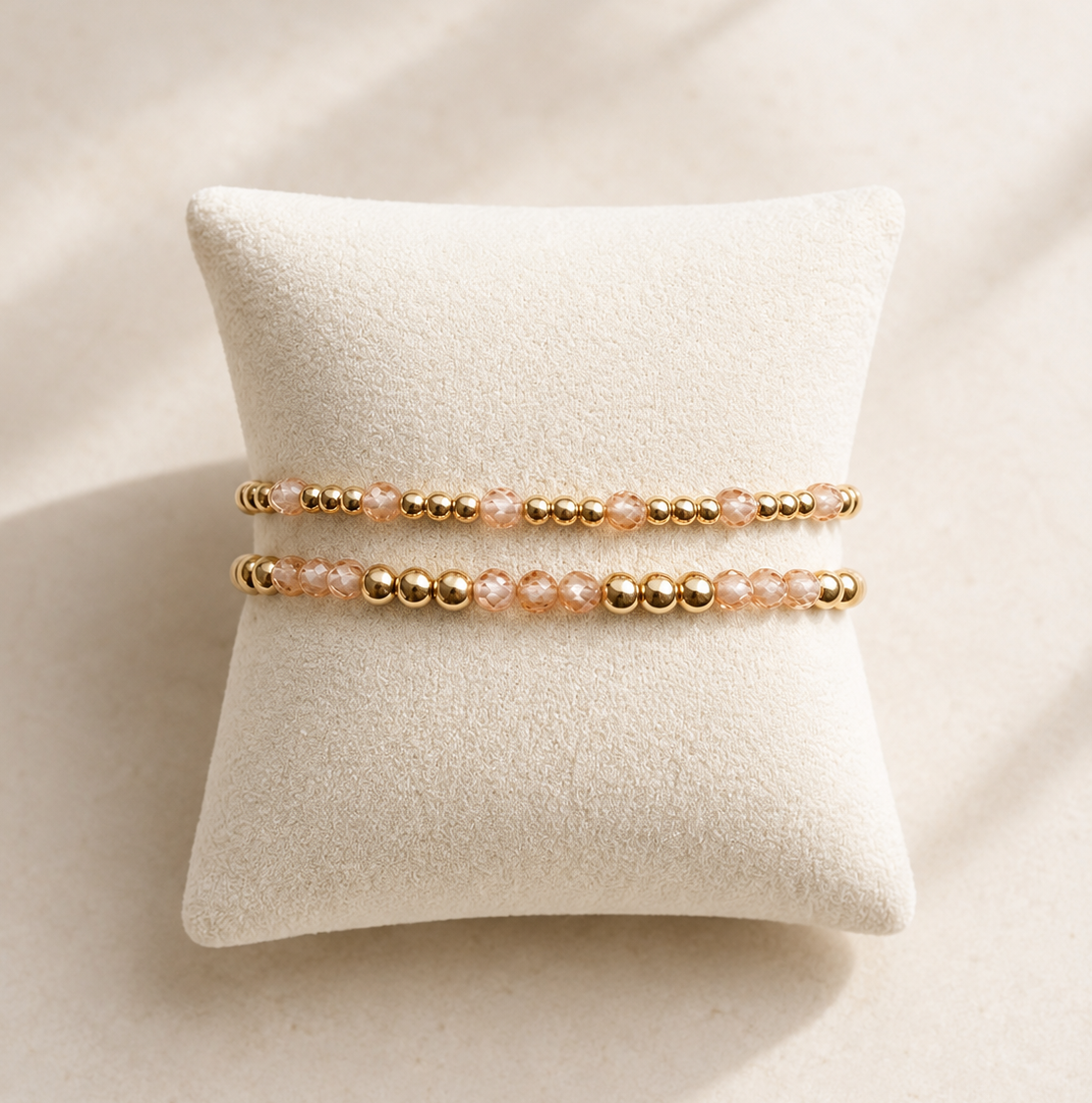 Twee gold filled armbanden met champagne zirkonia kralen op een beige sieradenkussen