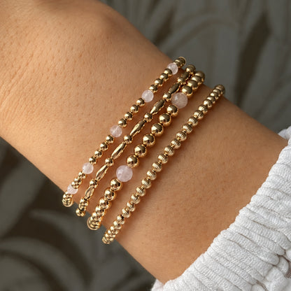 Gestapelde gouden kralenarmbanden en rozenkwarts armbanden van gold filled 14K, van Bedels & Bedels.