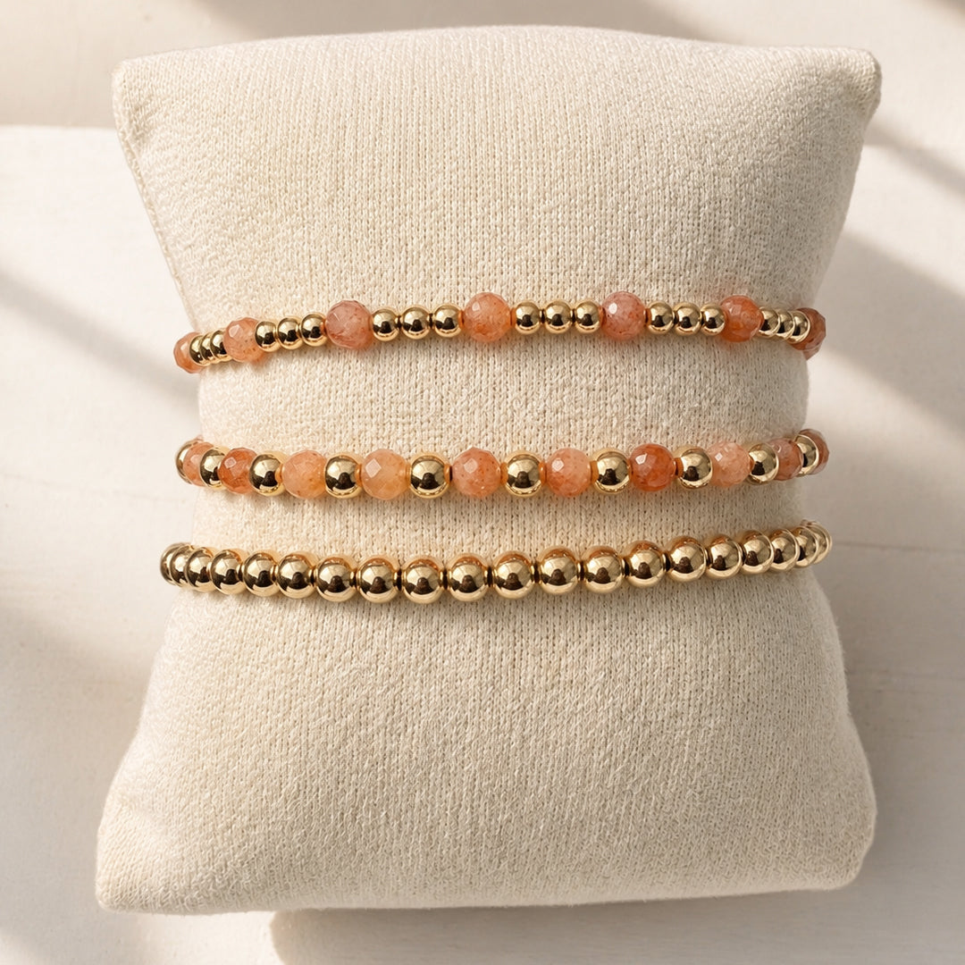 Gouden armbanden met gouden kralen en zonnesteen edelstenen op een sieradenkussen, van Bedels & Bedels.