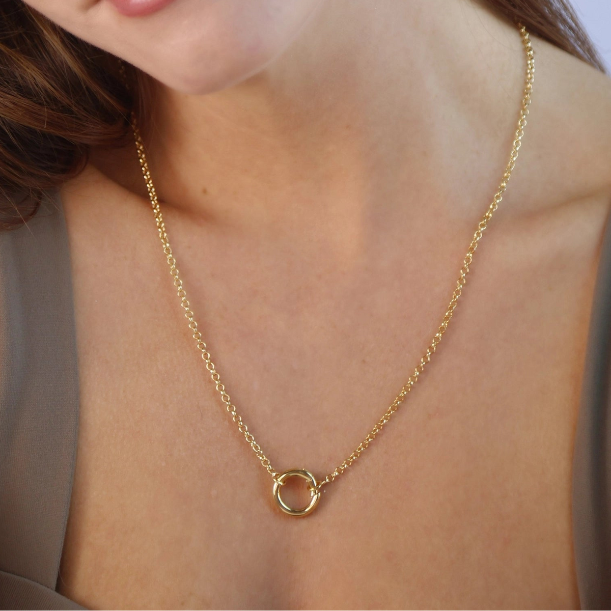 Fijne gouden ketting met ronde sluiting gedragen om de hals van een model met bruin haar